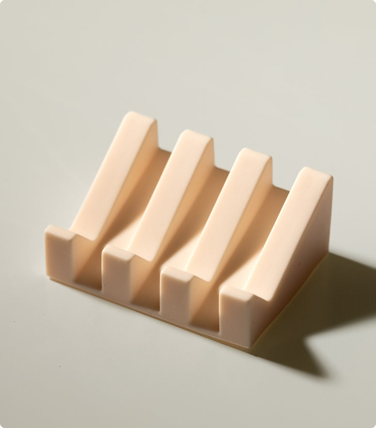 A minimalist light beige soap dish made of silicone featuring raised ridges for optimal air circulation and a clean, contemporary look.