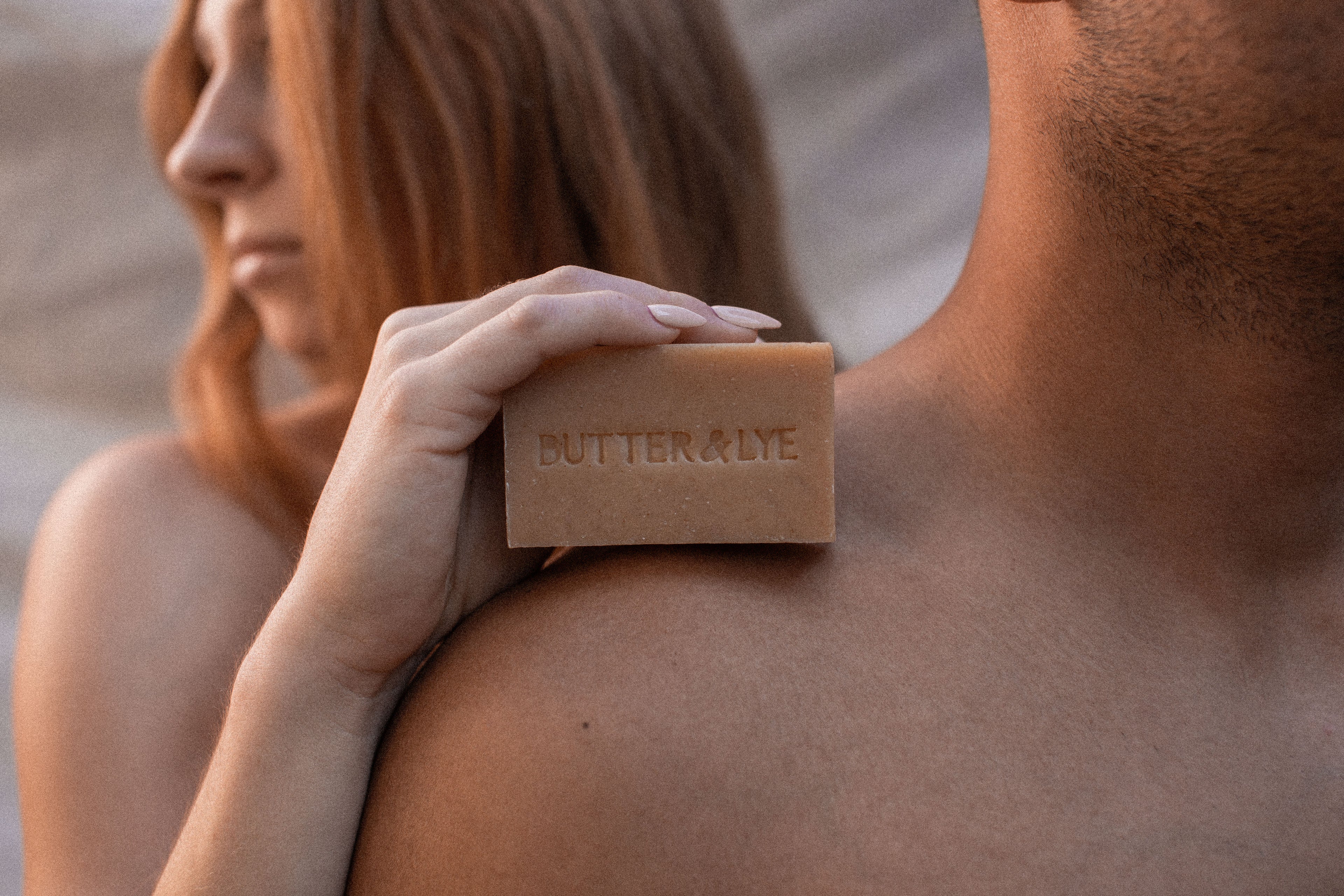 Person holding a bar of soap labeled 'Butter & Lyfe' on another person's shoulder.