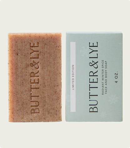 A bar of Butter & Lye, Radiant Winter Spice face and body soap, shown next to its mint-colored packaging. The brown, speckled soap conveys the rich, warm essence of cinnamon.