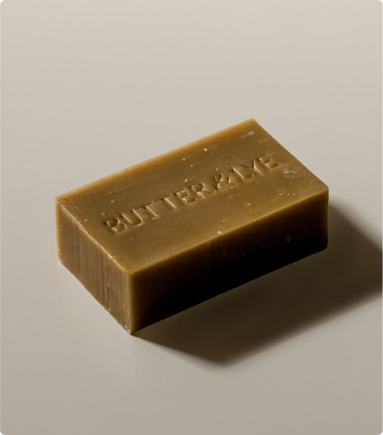 A rectangular, earthy green soap bar with the words "Butter & Lye" embossed on its surface, set against a neutral background. The soap has a smooth, matte texture with small natural imperfections.